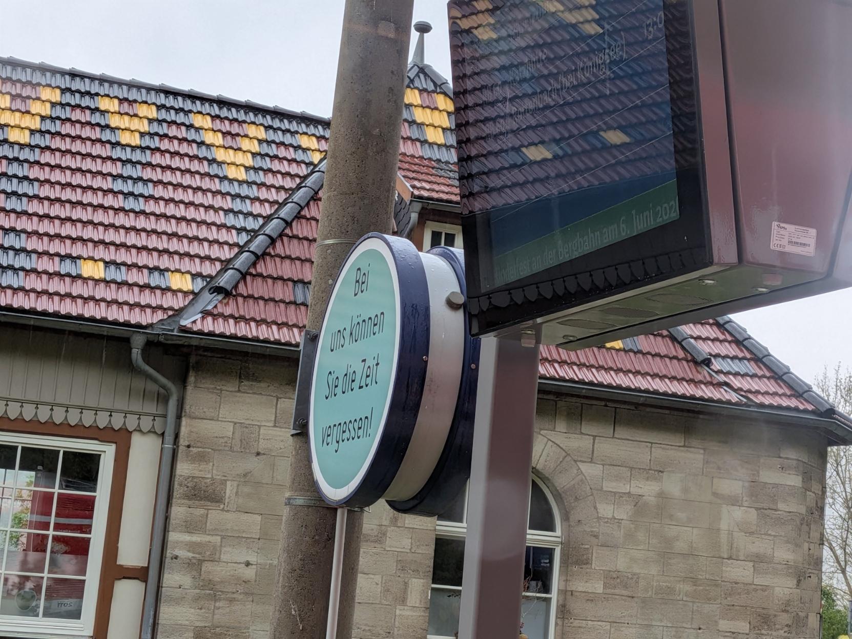 Bahnhofsuhr, auf einer Seite klebt ein Aufkleber "Bei uns können Sie die Zeit vergessen!"