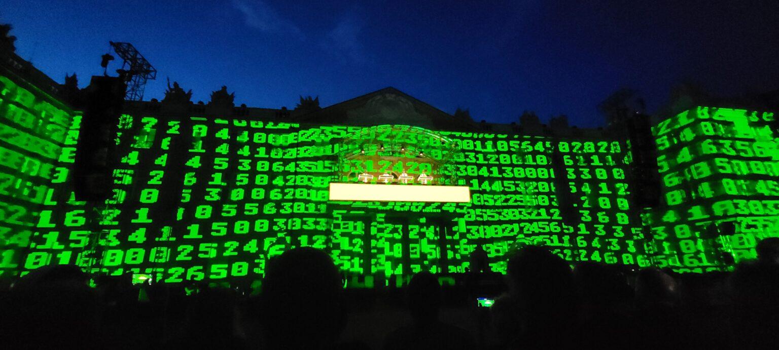 Kraftwerk auf dem Balkon vom Schloss Karlsruhe, während es von einer Projektion von vielen grünen Zahlen bestrahlt wird